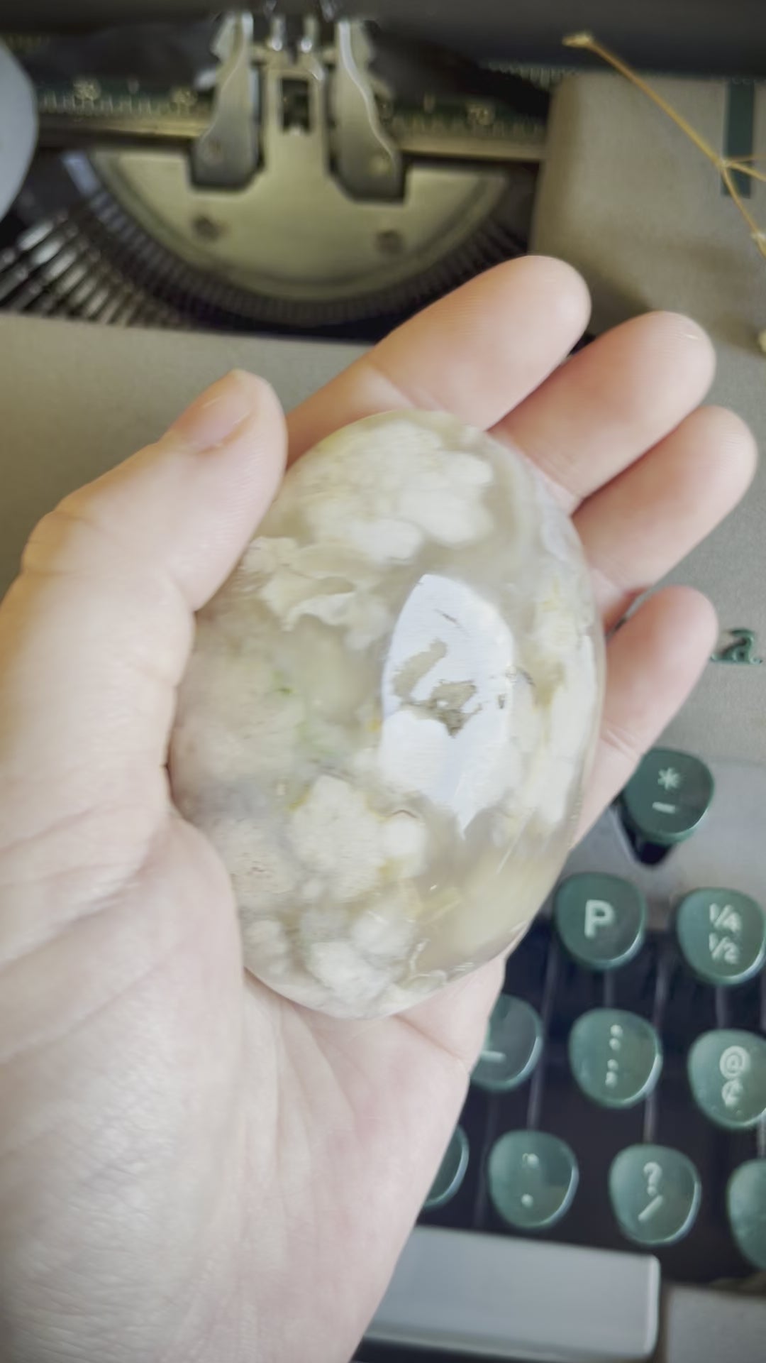 A flower agate palm stone held in a hand.