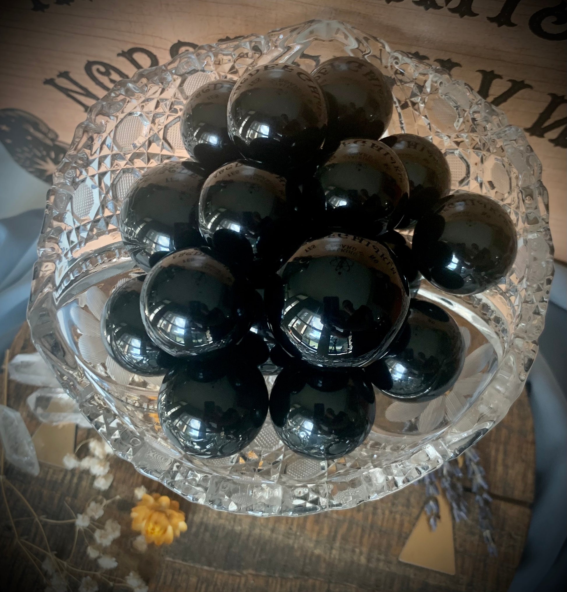 A clear crystal bowl full of reflective black obsidian spheres
