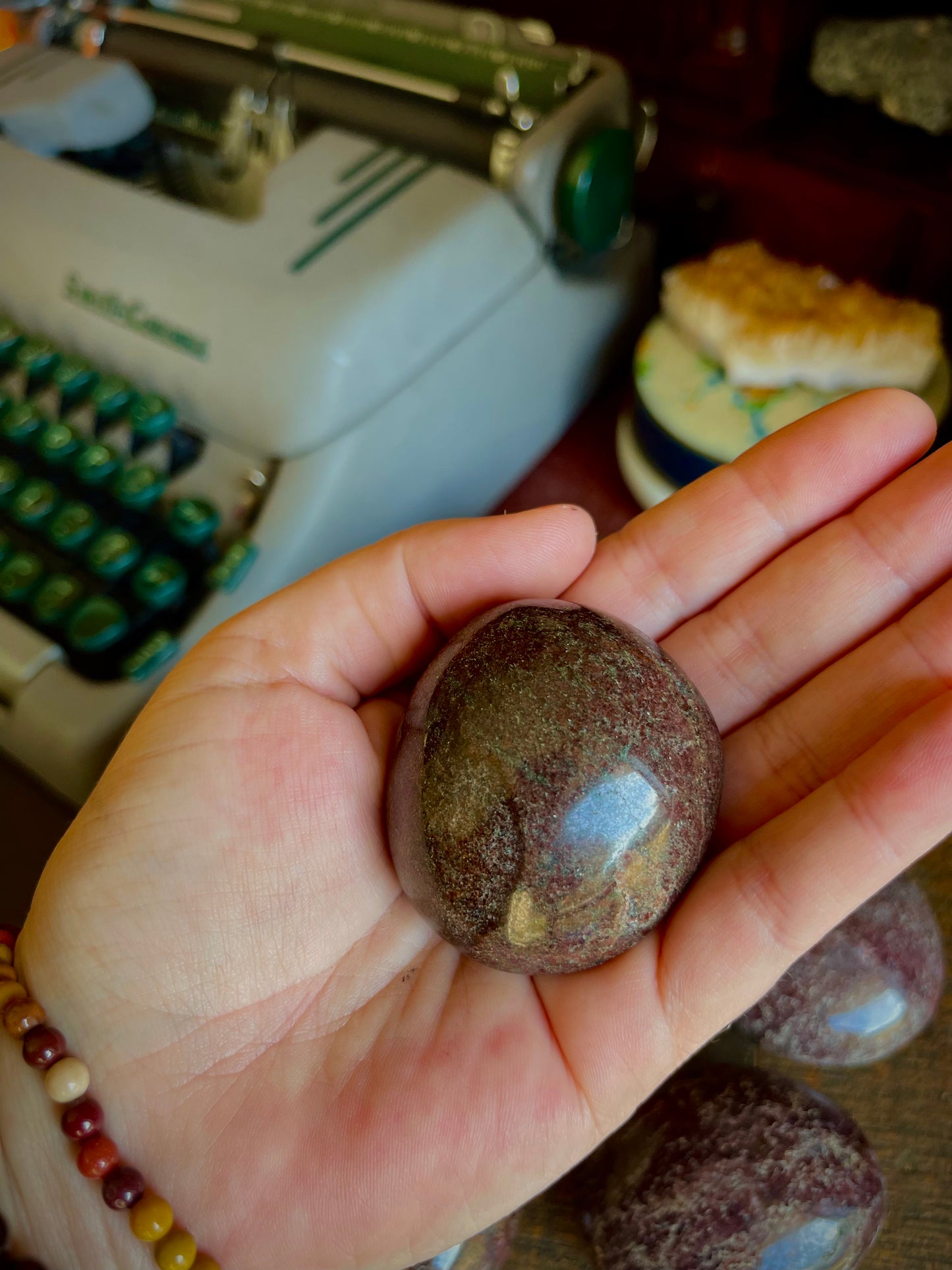 Garnet palm stone in a hand near a green typewriter.