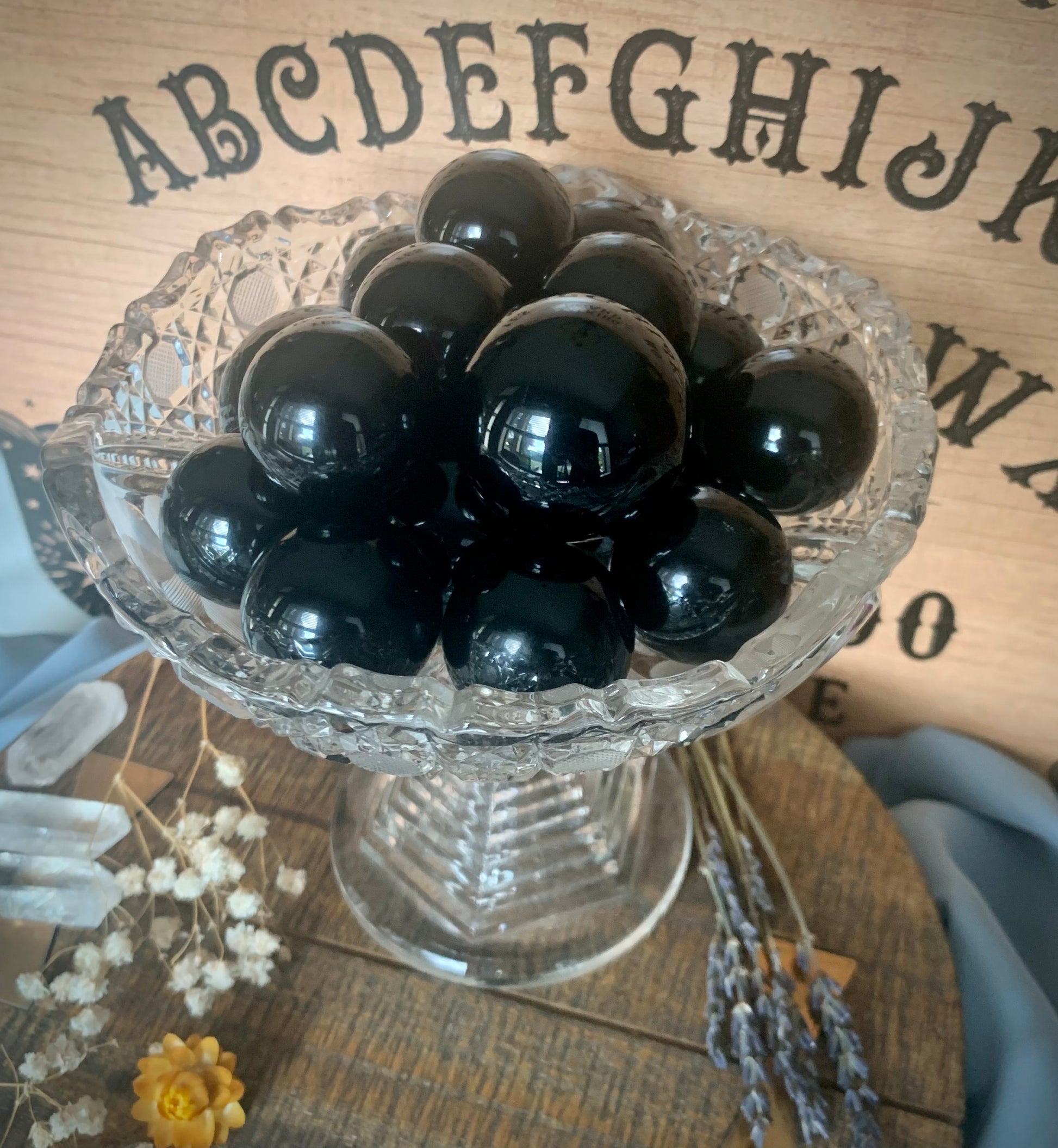 A clear crystal bowl full of reflective black obsidian spheres